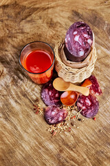 Country still life with sausage in a fabric casing with slices in a wicker vase, tomato juice and spoons with spices. Natural product, home atmosphere.
