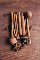 still life with fragrant cinnamon sticks, hazelnuts, clove buds and star anise on a wooden background, top view