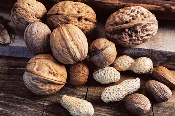 hazelnut, walnut, peanut and almond lying in a pile on a wooden background close-up