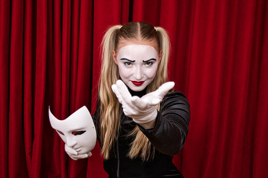 On stage, the focus is on a mime artist with a mask in his hand. Close-up portrait