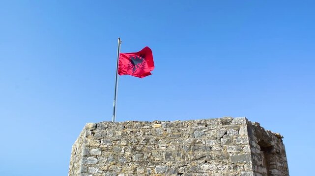 Albanian flag flies against a blue cloudless sky. Albania. Close up.