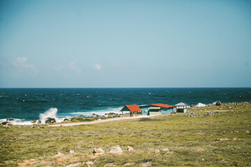 Coastal landscape featuring vibrant huts by the ocean at midday under a clear blue sky