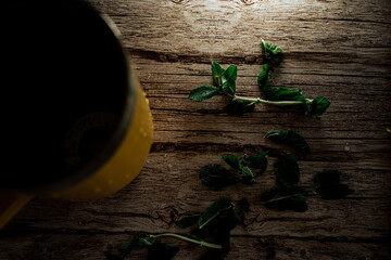 Fresh mint leaves are scattered organically across a textured wooden surface. This image highlights...