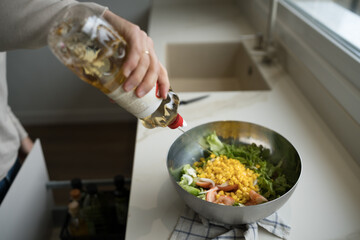 Woman dressing fresh salad with vinegar in modern kitchen