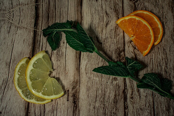 fresh mint leaves layered over slices of lemon and orange on a rustic wooden background. This vibrant composition suggests natural freshness, healthy ingredients, and refreshing beverage concepts. © Вікторія Оленич