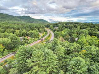 Scenic winding road through lush green forest with mountain views