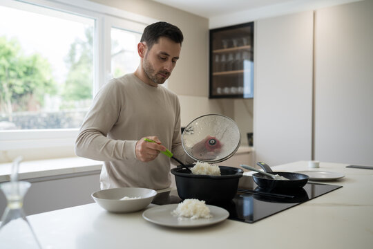 Man serving rice in modern kitchen, cooking and nutrition