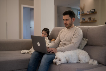 Father working from home with daughter and dog on sofa