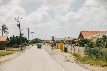 Colorful houses line a quiet road under a blue sky in a tropical village during midday