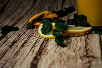 fresh mint leaves layered over slices of lemon and orange on a rustic wooden background. This...