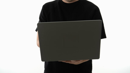 Person holding a laptop in front of a plain white background during a casual indoor activity