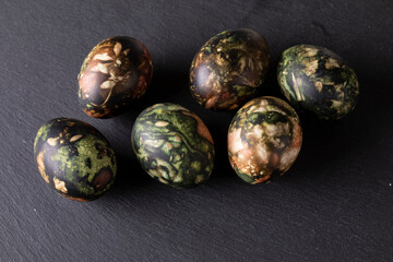 Easter decorations. Traditionally coloured Easter eggs on a black stone background. Top view, copy space.