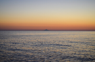Obraz premium The ocean is calm and the sky is a beautiful orange color. The sun is setting, creating a warm and peaceful atmosphere