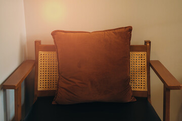Wooden Chair. Cozy Wooden Chair with Plush Brown Cushion Against Soft Neutral Wall