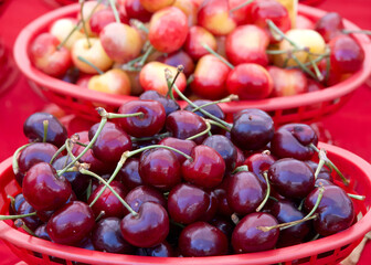 Close up on basket of ripe red bing cherries with yellow rainier cherries in basket behind it.