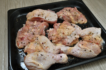 pieces of raw chicken with pepper and garlic on a baking sheet, ready for baking