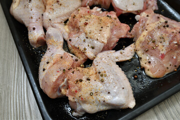 pieces of raw chicken with pepper and garlic on a baking sheet, ready for baking