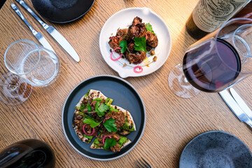 Romantic dinner for two. Two plates with starters or appetizers on a round wooden table.
