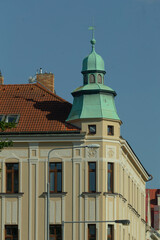 There is a building that features a distinctive green tower located on its uppermost section,...