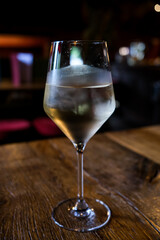 Glass of white wine On a wooden table in a bar. Dark romantic atmosphere.