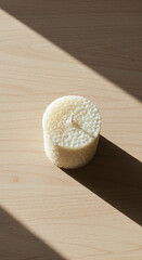 Cylinder candle on wooden surface with sunlight and shadow