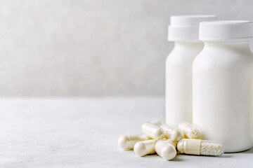 Bottles of white milk yogurt (kefir) and capsules with probiotic on a light background. The concept of an alternative to pills and a healthy diet
