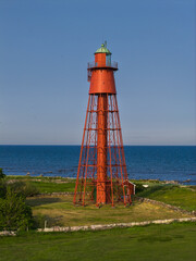 Arial view of a red and white lighthouse on the coast of Öland, Sweden surrounded by rugged...