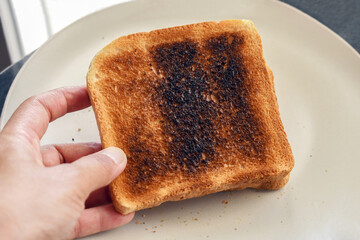 Burnt toast in woman hand. Cooking failed concept.