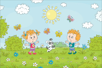 Happy little kids and their cheerful puppy playing with colorful butterflies flying around a flower green field on a sunny summer day, vector cartoon illustration