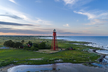 Arial view of a red and white lighthouse on the coast of Öland, Sweden surrounded by rugged...