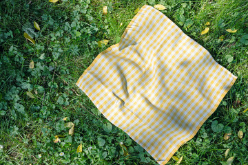 Yellow checkered cloth,checked towel top view on green grass.Food advertisement blank.Picnic towel empty space.Tablecloth outdoor.