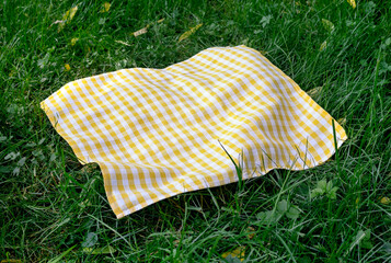 Yellow checkered cloth,checked towel top view on green grass.Food advertisement blank.Picnic towel empty space.Tablecloth  outdoor.