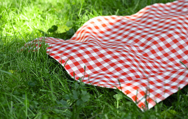 Red checkered picnic towel plaid on grass, tablecloth outdoors.Food advertisement template.