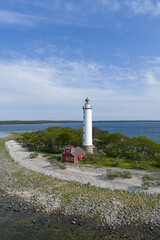 Arial view of a red and white lighthouse on the coast of Öland, Sweden surrounded by rugged...