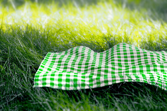 Green checked picnic napkin,tablecloth on grass empty food advertisement space. Plaid checkered towel, cloth.Summertime template. - Powered by Adobe