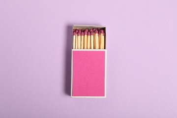 Matches in box on violet background, top view. Mockup for design
