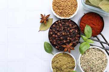 Different aromatic spices on white tiled table, flat lay. Space for text