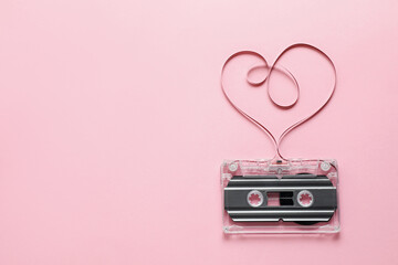 One audio cassette with heart shaped magnetic tape on pink background, top view. Space for text