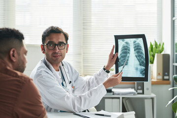 Middle aged Caucasian male doctor explaining chest X-ray results to middle aged man during diabetes...