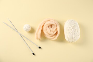 Felting wool and knitting yarn with needles on beige background, flat lay