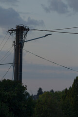 A tall telephone pole with numerous wires and cables hanging down from it, supporting the overhead...