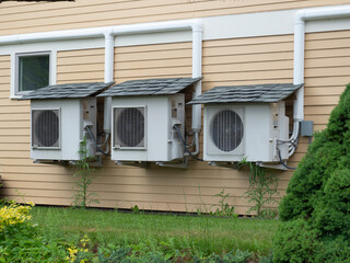 Three heat pumps with small shingle roofs to make them last longer