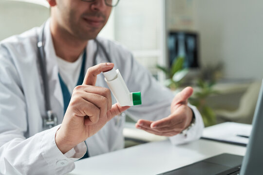 Middle aged Caucasian male doctor explaining use of inhaler device to unseen patient during medical consultation in modern clinic, demonstrating proper technique for diabetes management education