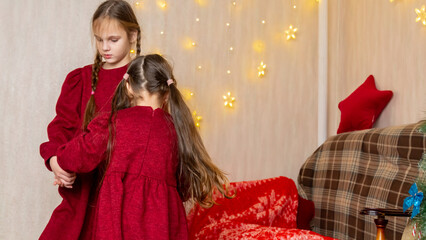 Happy positive kids have fun on Christmas day at home. Children dance to New Year music during...