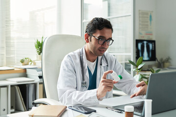 Middle aged Caucasian male doctor consulting patient with diabetes via video call, holding...