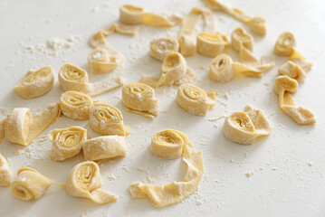 Freshly made raw pasta noodles on a white surface.