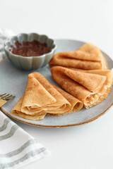 Crepes with chocolate cream and coffee on white wooden table. Pancake day, Maslenitsa