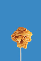 Golden pancakes on a fork against a vibrant blue background.