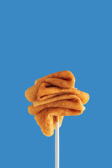 Golden pancakes on a fork against a vibrant blue background.