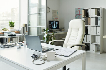 Empty medical office showing desk with laptop, blood pressure monitor, clipboard, prescription bottles, stethoscope, indicating preparation for patient with diabetes consultation